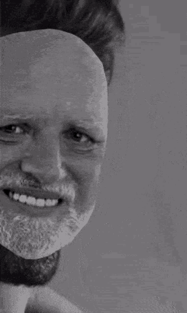 a man with a beard is smiling in a black and white photo .