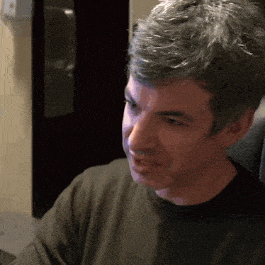 a man with gray hair is wearing a black sweater