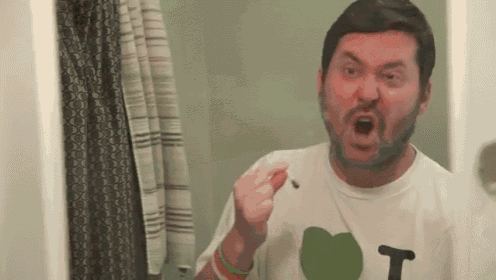 a man in a white shirt with the letter t on it is brushing his teeth