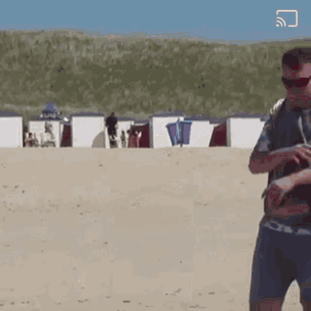a man wearing sunglasses is standing on a sandy beach