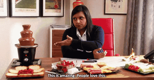 a woman is sitting at a desk with a chocolate fountain in the background and says this is amazing . people love this .
