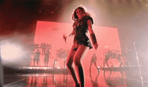 a woman is dancing on a stage in front of a large screen .