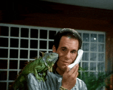 a man with a lizard on his shoulder is talking on a phone