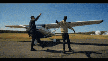 two men standing in front of a small plane with the letters hafi on the wing