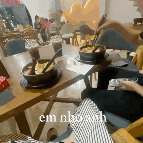 a person is sitting at a table with a bowl of food on it and the words em nha anh written on the bottom