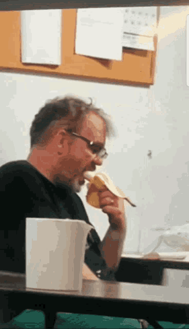 a man sitting at a table eating a sandwich