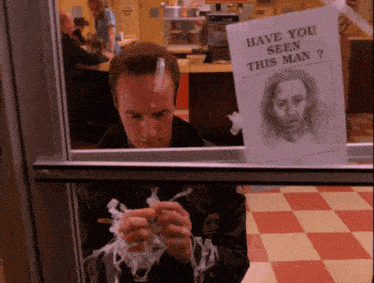 a man with a bandage on his head looks through a window at a poster that says have you seen this man