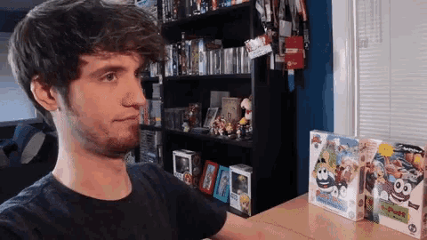 a man stands in front of a shelf full of toys including a box of spongebob squarepants