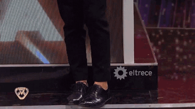 a person standing in front of a eltrece logo