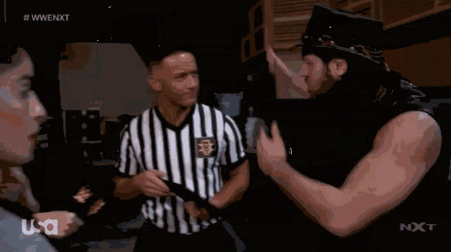 a man in a cowboy hat talks to a referee in a striped shirt