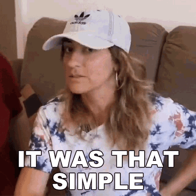 a woman wearing a hat and tie dye shirt is sitting on a couch .