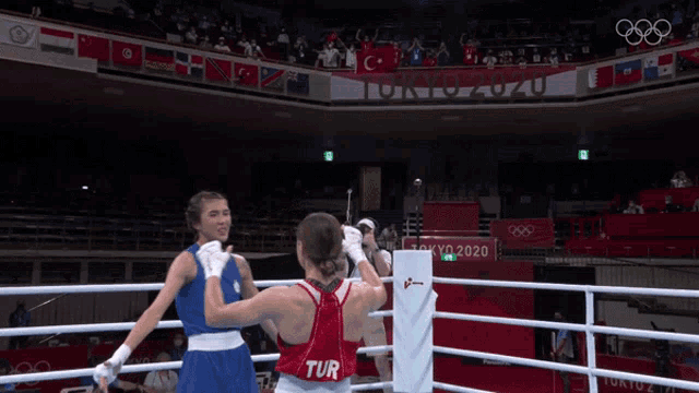 two female boxers are fighting in a ring with tokyo 2020 written on the wall behind them