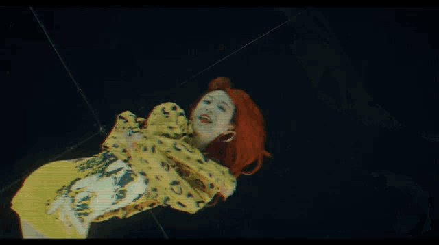 a woman with red hair is wearing a yellow and black leopard print hoodie .