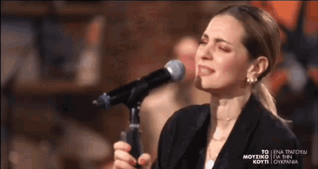 a woman is singing into a microphone while wearing earrings .