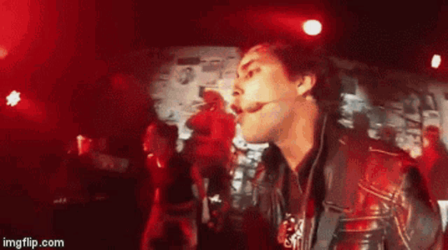 a man in a leather jacket is singing into a microphone in front of a crowd ..