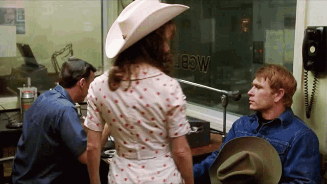 a woman in a cowboy hat is standing in front of a window that says mcdfw on it