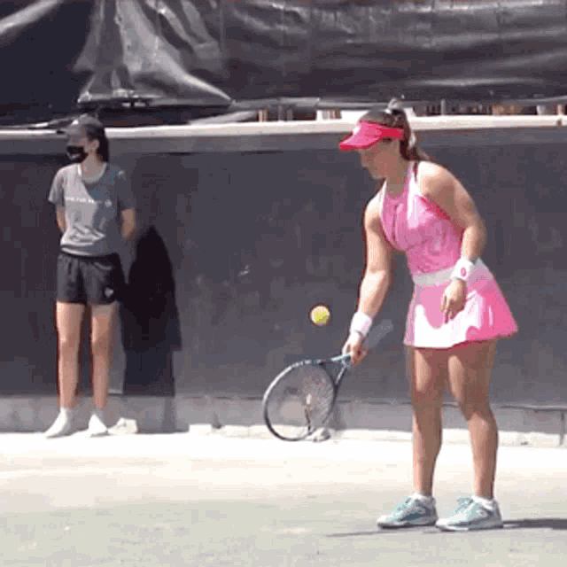 a woman in a pink dress is holding a tennis racket