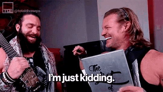 a man with a beard is holding a guitar and another man is holding a laptop and laughing .