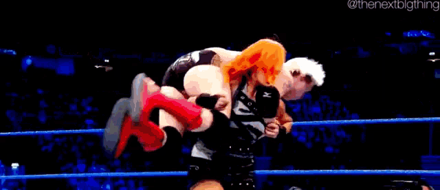 two wrestlers are wrestling in a ring with a referee watching .