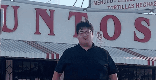 a man standing in front of a sign that says " juntos "
