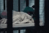 a person is laying on a bed in a prison cell .