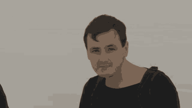a man wearing a black shirt with a backpack around his neck