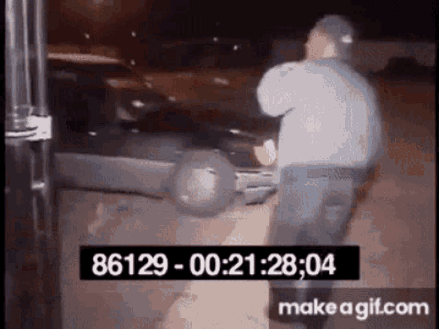 a man is standing next to a car in a parking lot with a time stamp .