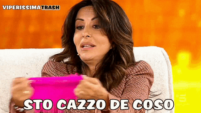 a woman holding a pink item with the words sto cazzo de coso on it