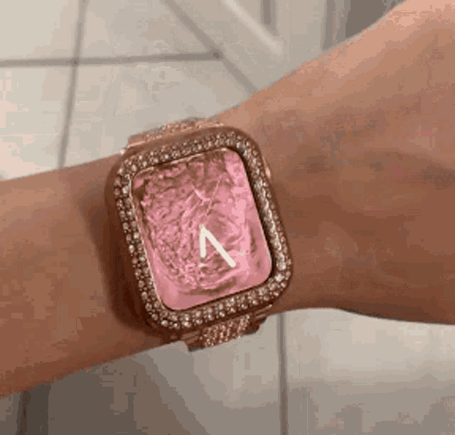 a woman is wearing an apple watch on her wrist with a pink face .