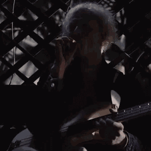 a man with white hair is playing a guitar in the dark