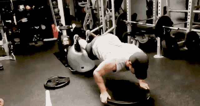 a man is doing push ups in a gym with a dumbbell on the floor