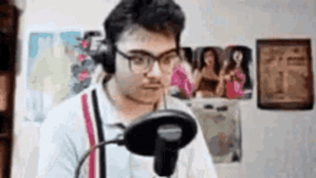 a man wearing headphones is sitting in front of a microphone .