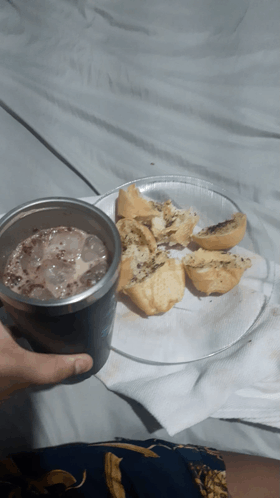 a person is holding a cup of iced chocolate next to a plate of food