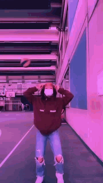 a person wearing a mask is standing on a basketball court holding a basketball .