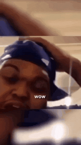 a woman wearing a blue hat is looking at herself in a mirror and says wow .