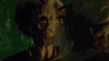a man in a gas mask is talking to another man .