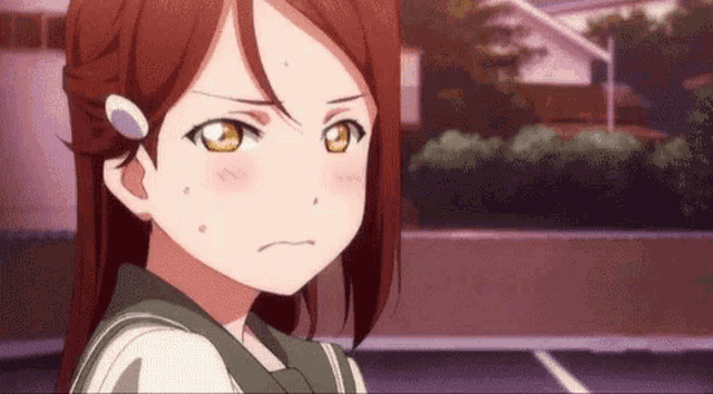 a close up of a girl with red hair and yellow eyes making a face .