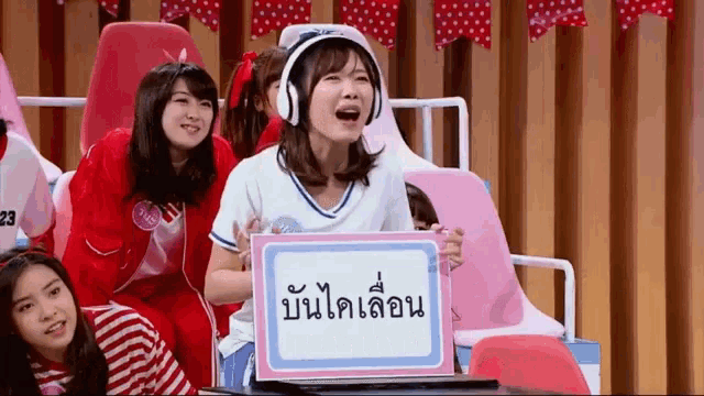 a girl wearing headphones is holding a sign that says ' a ' on it