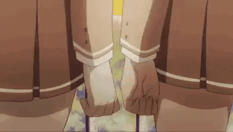 two girls in school uniforms are holding hands in a close up .