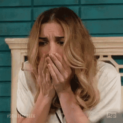a woman is covering her face with her hands while sitting on a bench .