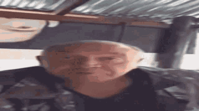 a man with a bald head is sitting in front of a window .