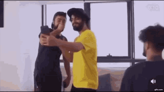 two men are standing next to each other in a living room .