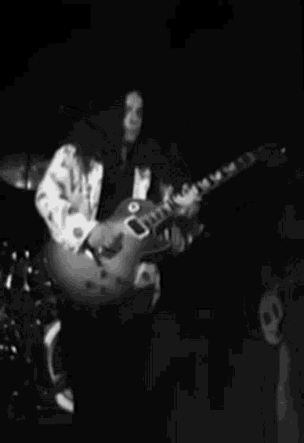 a man is playing a guitar in a black and white photo .