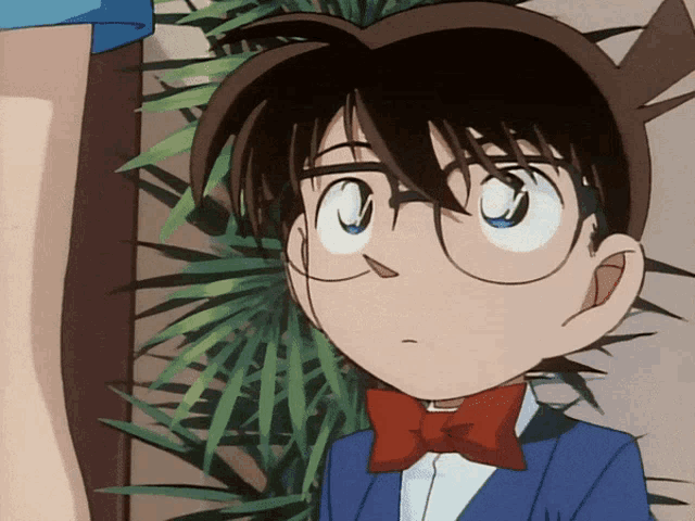a boy with glasses and a red bow tie looks at the camera
