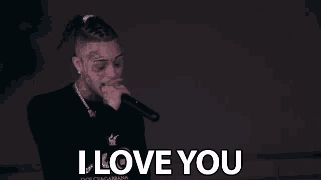 a man singing into a microphone with the words i love you behind him .