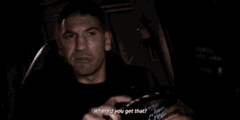 a man is sitting in a dark room with a bottle of stark 's water in his hand .