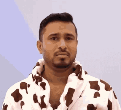 a man with a beard is wearing a brown and white cow print robe .