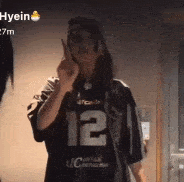 a woman is wearing a jersey with the number 12 on it and giving the middle finger .