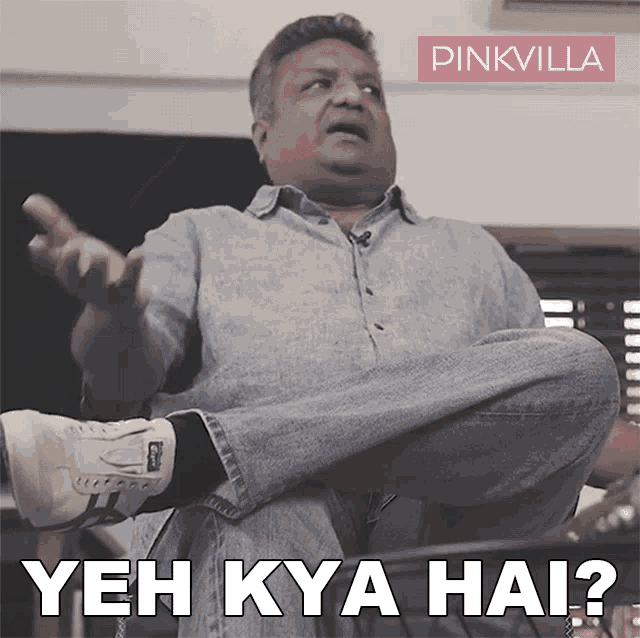 a man sits with his legs crossed and says " yeh kya hai " in white letters