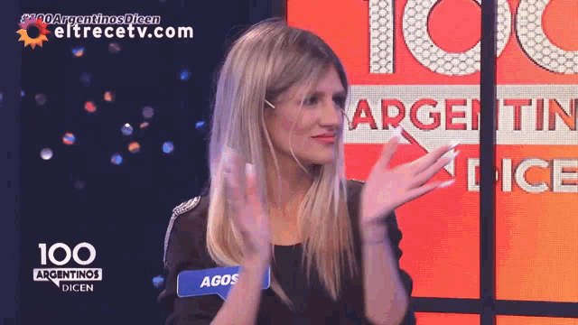 a woman applauds in front of a sign that says 100 argentinas dien